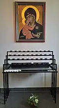 Im Eingangsbereich hängt eine Marienikone, vor der ein Opferlichtständer steht