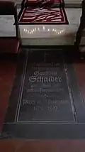 Grabstein vorm Seitenaltar im nördlichen Querschiff mit der Aufschrift: Geistl. Rat Msgr. Gottfried Schaider, Pfarrer an St. Pankratius 1878–1937