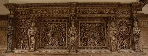 und ein geschnitzter offener Kamin mit männlichen und weiblichen Figuren im Wechsel mit grotesken Köpfen.