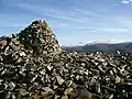 Der Gipfelcairn des Meall a’ Bhuachaille, im Hintergrund der 1090&nbsp;Meter hohe Bynack More