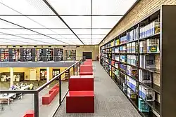 Galerie im TIB-Standort Technik & Naturwissenschaften mit Arbeitsplätzen, Bücherregalen und Blick in den offenen Innenbereich.