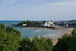 Blick auf bunte Häuser hinter einem kleinen Hafen bei Ebbe, links sind zwei Häuser mit Rampen zum Herablessen von Rettungsbooten.