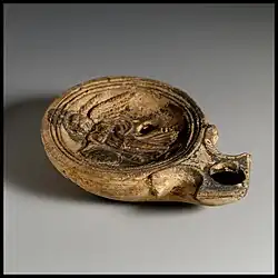 Römische Öllampe aus Ton in Dreiviertelansicht, auf dem Spiegel das Bild einer Victoria mit Schild