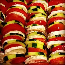 Detailaufnahme des Tians, das das Gemüse und den Käse in gleichmäßig geschichteter Reihung zeigt.