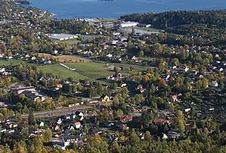 Blick vom Skaugumsåsen&nbsp;– das Holmen Senter ist anhand der Fußgängerbrücke unmittelbar vor der Küstenlinie zu erkennen