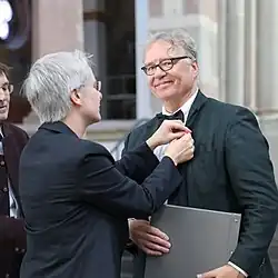 Verleihung des Severins-Bürgerpreises 2019 an Eusebius Wirdeier durch Vereinsvorsitzende Ursula Jünger. Sie steckt dem Preisträger eine Anstecknadel an.