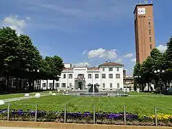 Der Platz Marconi mit Garten, Brunnen und Rathaus; Turm mit Uhr zur Rechten