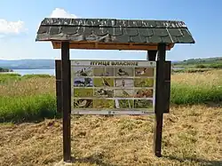 Schild auf einer Wiese mit dem Vlasinasee im Hintergrund