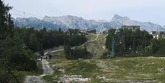 Rjava skala im Norden des Berges: Seilbahnbergstation und Schutzhütte Koča Merjasec na Voglu. Hinten rechts der Triglav.