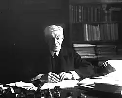 Person an einem Schreibtisch sitzend in einem Arbeitszimmer ab Oberkörper schwarzweiß