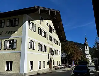 Gasthof Oberwirt mit der Kirche St. Sebastian im Hintergrund