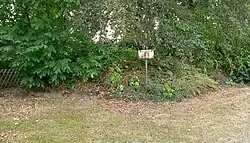 Wallinnenseite zum Friedhof mit Hinweisschild zum Bodendenkmal („Bodenentnahme strengstens untersagt“)