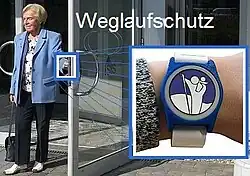 Weglaufschutz: Eine Seniorin verlässt das Gebaeude mit Weglaufschutz am Handgelenk