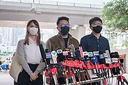 Agnes Chow, Ivan Lam und Joshua Wong stehen vor Mikrofonen der Presse.