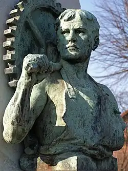 Symbolfigur „Arbeit“ mit Zahnrad und Hammer