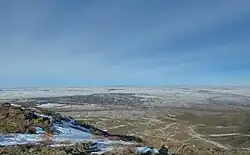 Schansügirow aus südöstlicher Richtung gesehen, die Siedlung liegt in der Ebene, während im Vordergrund die Gebirgsränder erkennbar sind